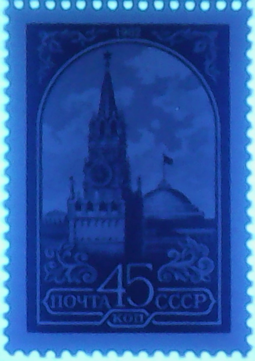 Zdjęcie ilustracyjne: The Soviet Union 1984 CPA 5510 stamp under 254nm UV on fluorescent background (13th standard issue of Soviet Union. 6th issue. Spasskaya Tower and the headquarters of the Council of Ministers).jpg
