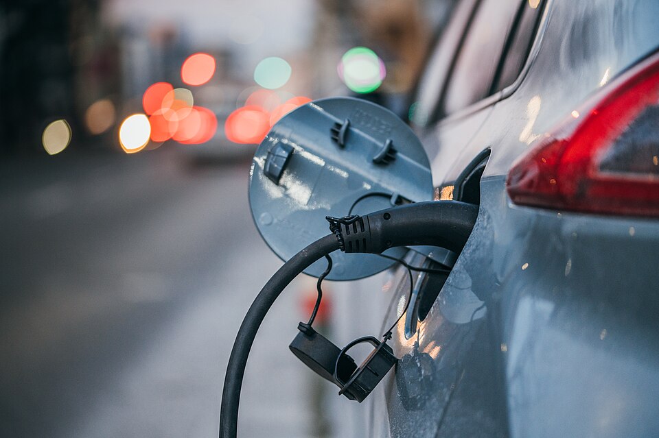 Zdjęcie ilustracyjne: Close-up of an electric car charging. Traffic lights in a blurry background.jpg